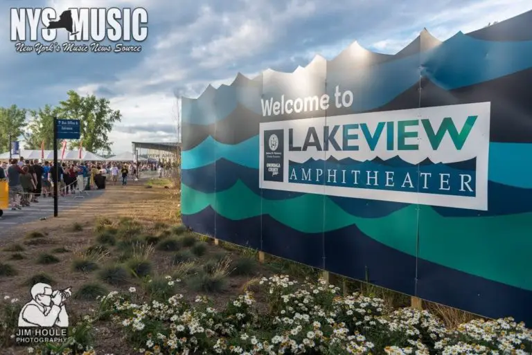 People wait in a line next to a blue sign that reads "Welcome to Lakeview Amphitheater". 
