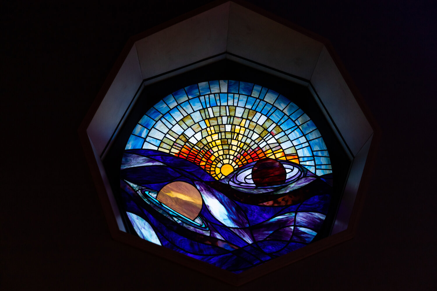 A spherical ceiling stained glass display of a solar system.