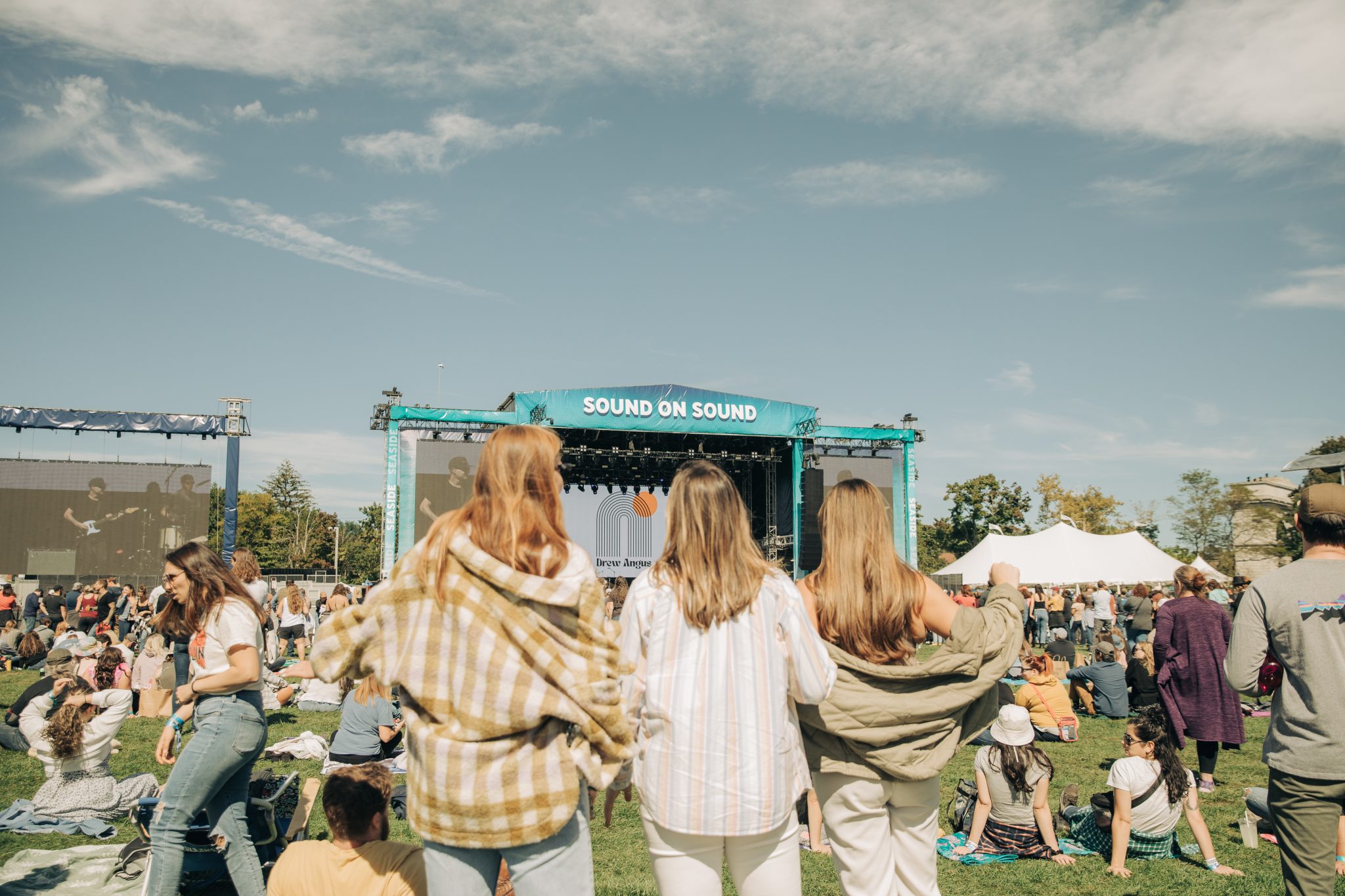 Picture from 2022 Sound On Sound Festival with three girls standing side by side in front of the stage.