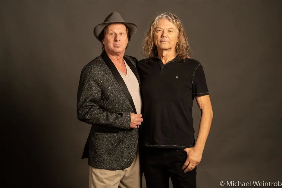 Jerry Harrison & Adrian Belew standing in front of a gray backdrop.