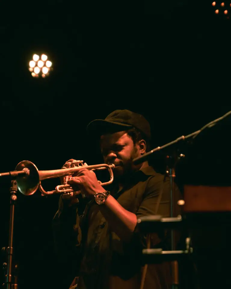Ambrose playing the trumpet with his eyes closed in a dark room.
