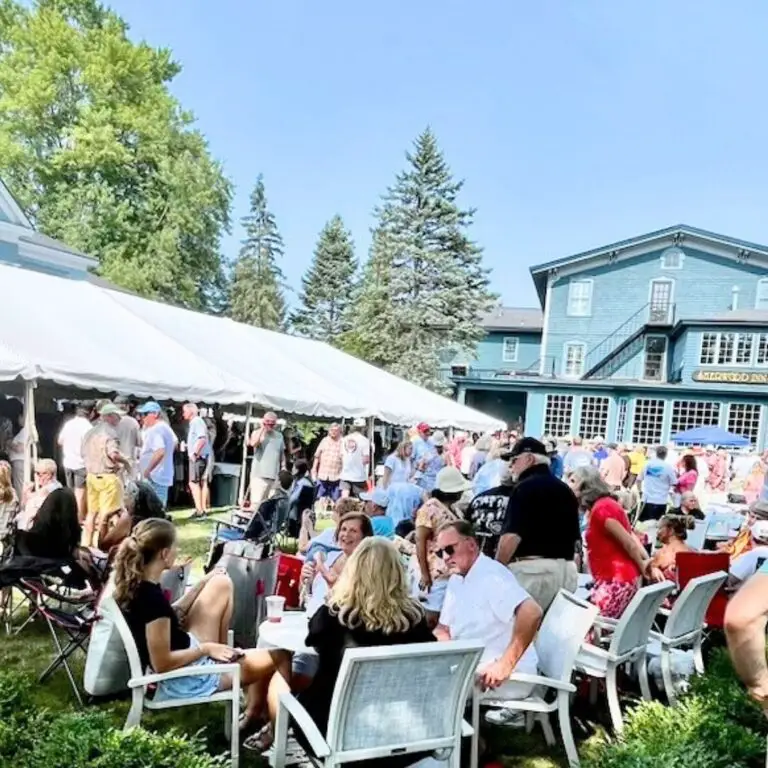 Photo of audience at the Sherwood Inn. People sitting at tables and standing under a tent in the background