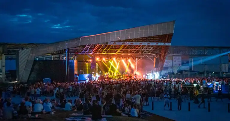 Terminal B at night with a packed crowd and bright green and orange lights on stage