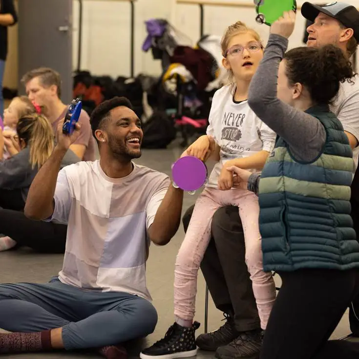 Dancers lead child in movement based workshop with music