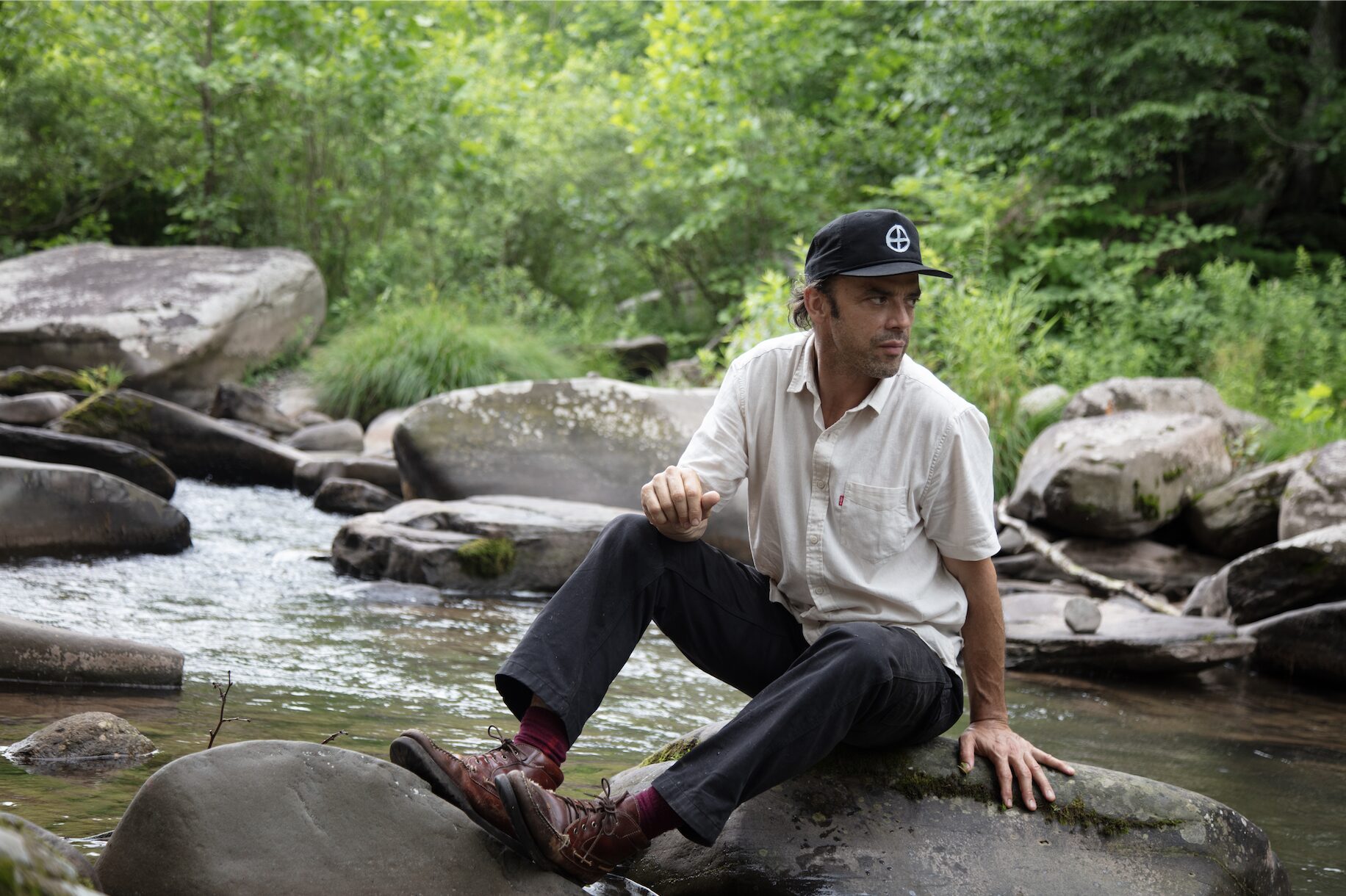 Matthew O'Neil sitting on rocks next to a river stream